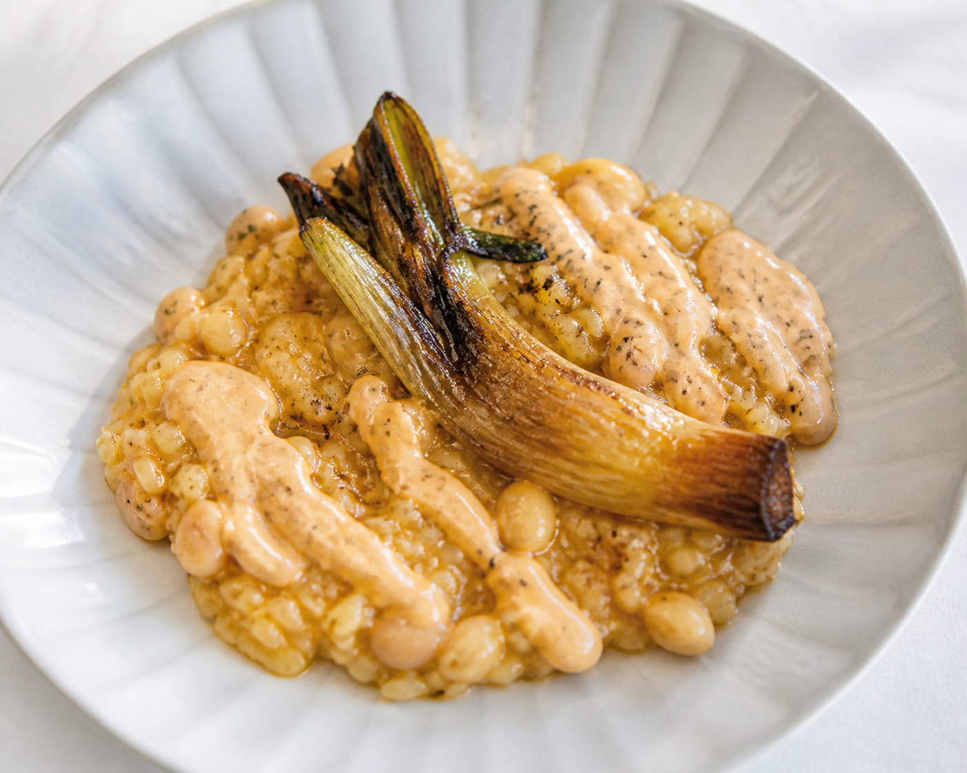 Creamy rice with roasted calçots, buttery beans, and light romesco yogurt cream