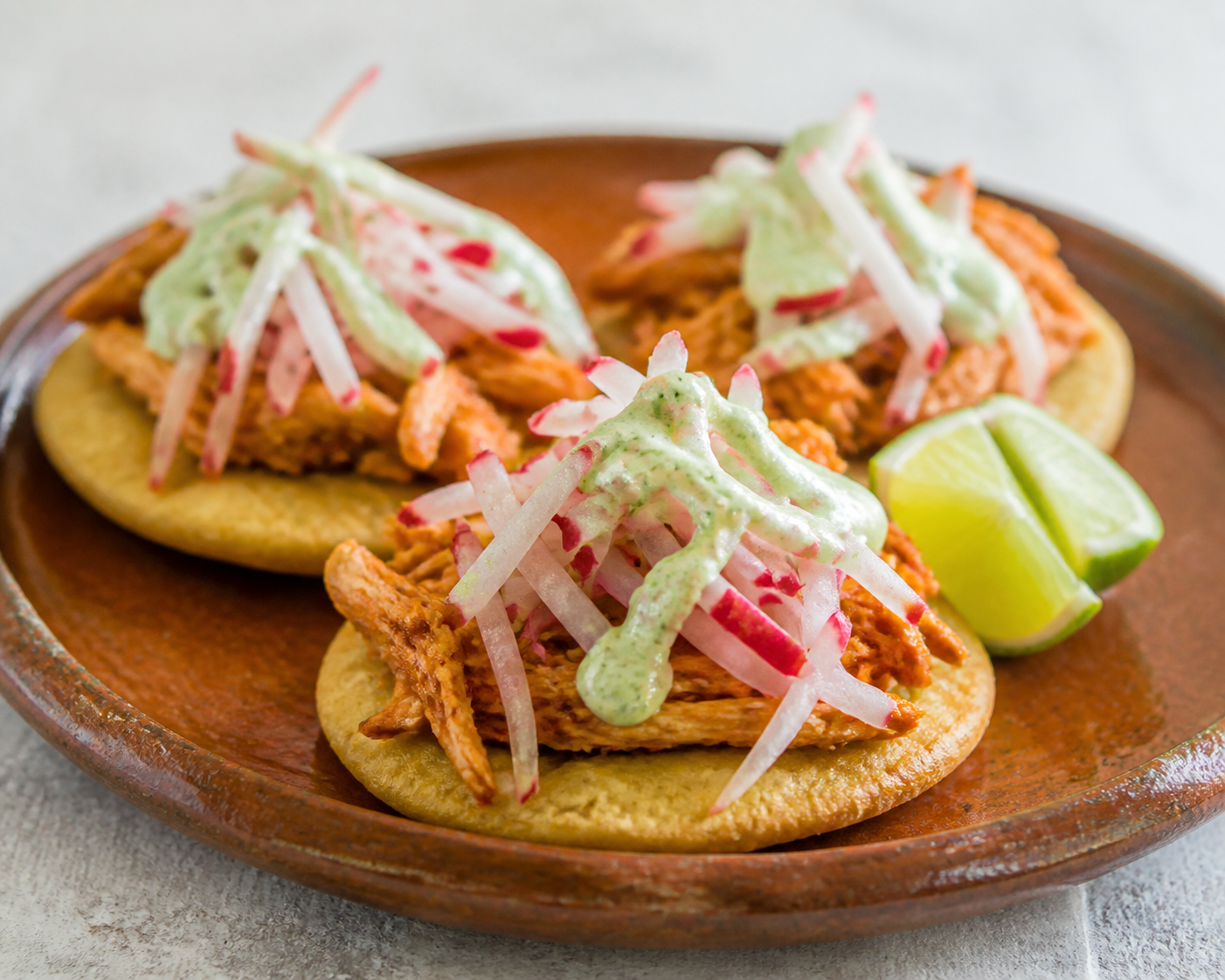 Chalupitas salvadoreñas de maíz y pollo achiotado con ensalada de rábano y crema de limón