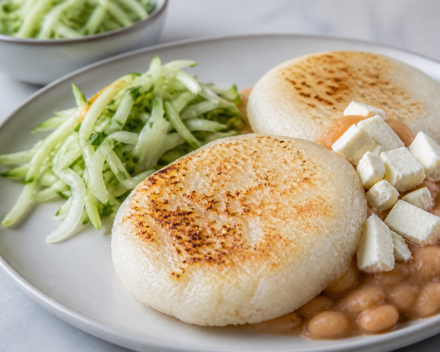 Rice Pupusas with Spiced White Beans and Queso Duro Blando, served with Cucumber Slaw