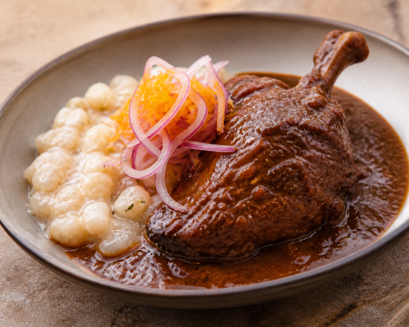 Seco de Pato con Tomate de Árbol y Cerveza Negra, acompañado de Mote Cremoso y Cebolla Curtida de Naranja