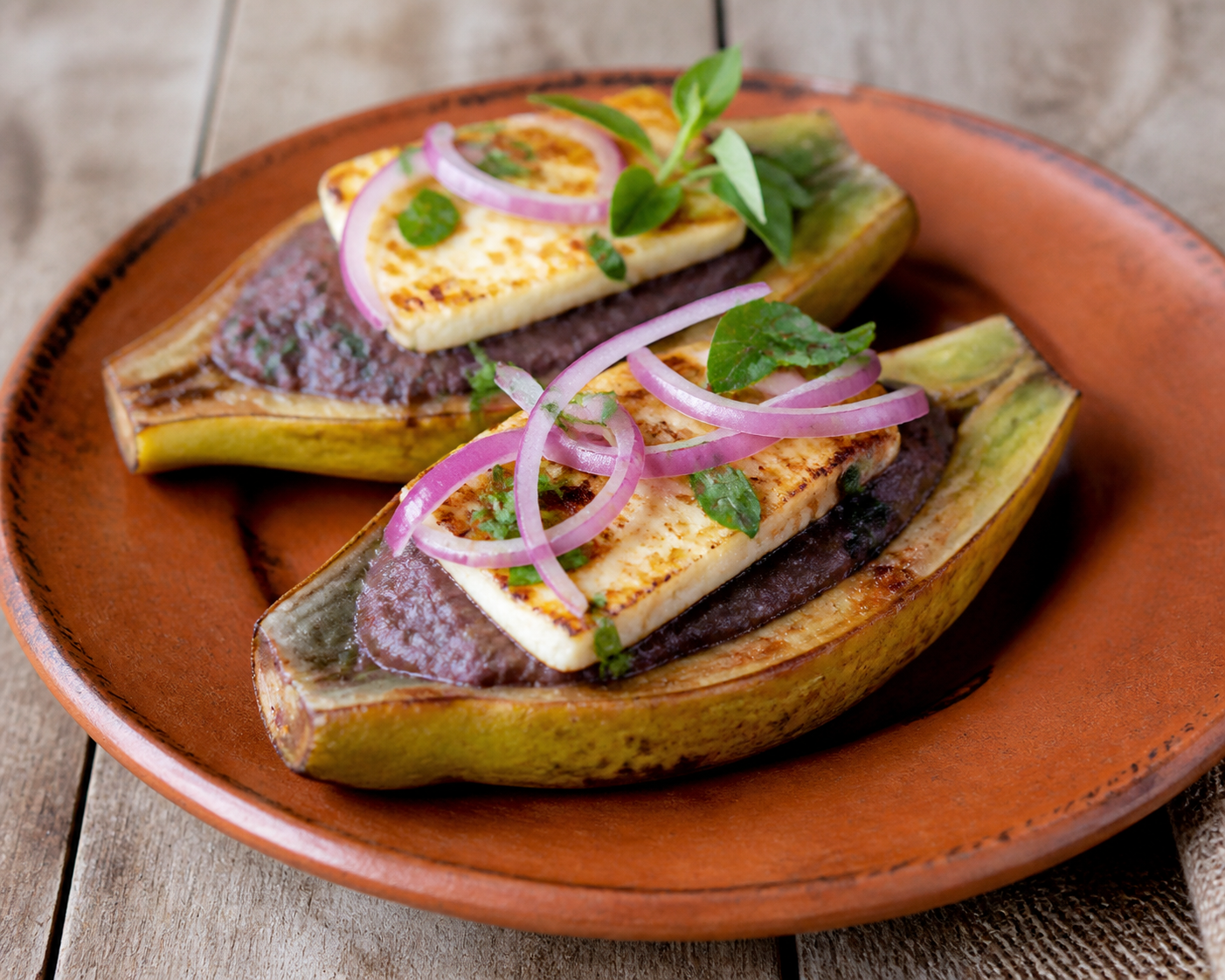 Canoas salvadoreñas de plátano verde con crema de frijol rojo al chipilín y queso fresco dorado