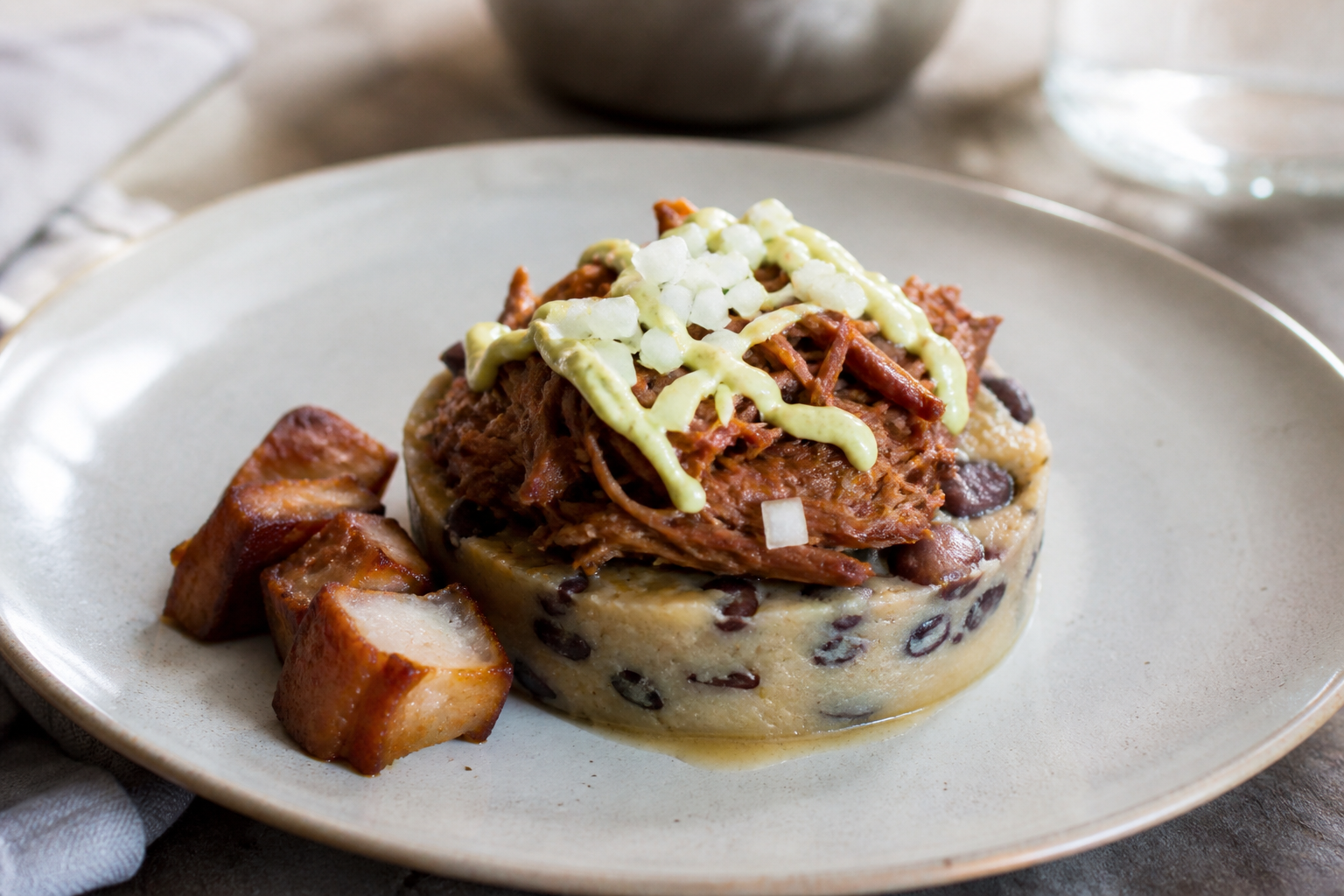 Creole mapuey and black bean timbale with citrus panela pulled pork and avocado cream