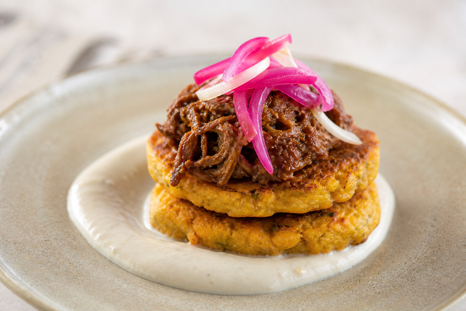 Sweet corn and squash cakes with gently cocoa-braised shredded beef, white bean cream, and pickled onion