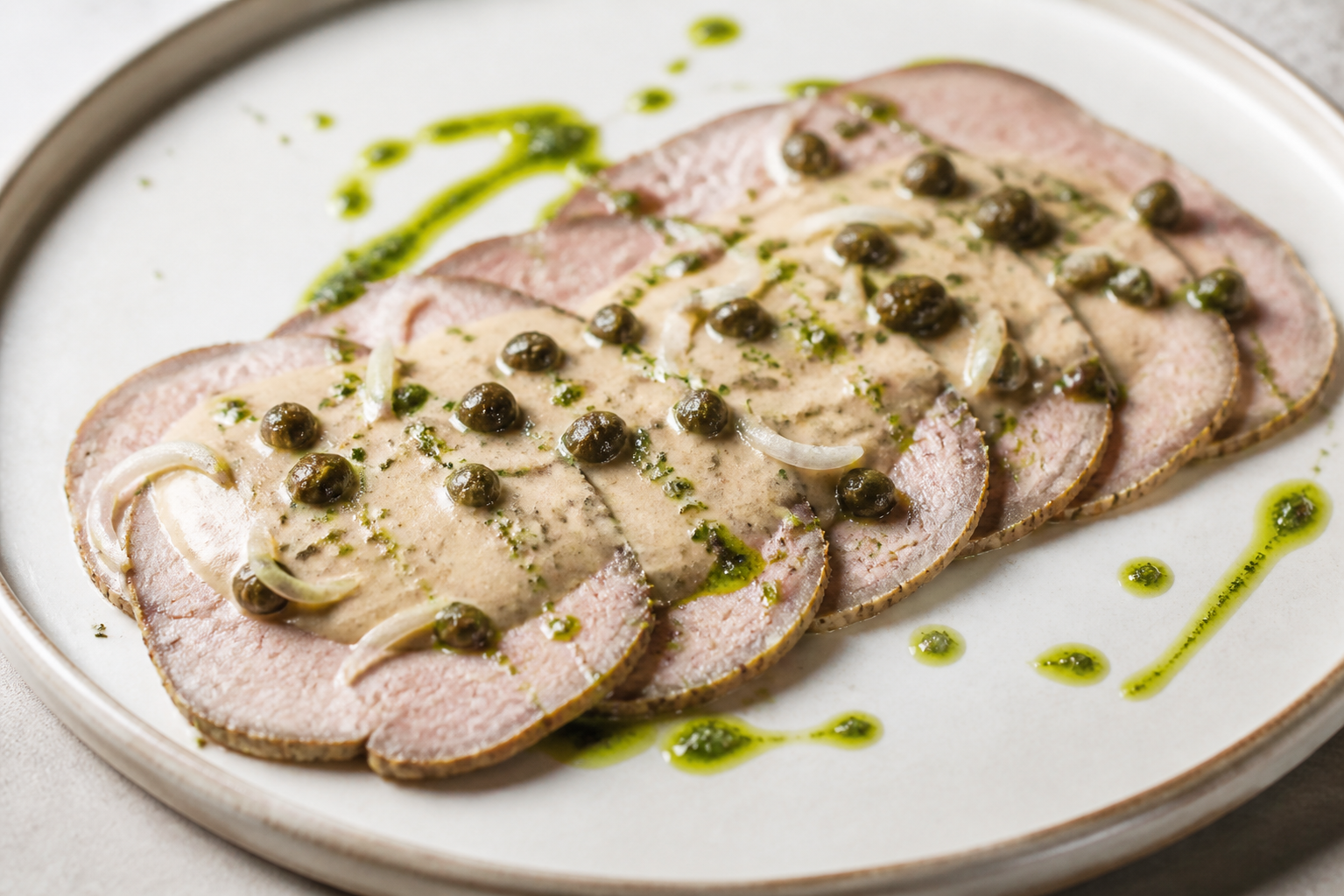 Vitel toné criollo con atún ahumado, alcaparras crocantes y aceite de perejil