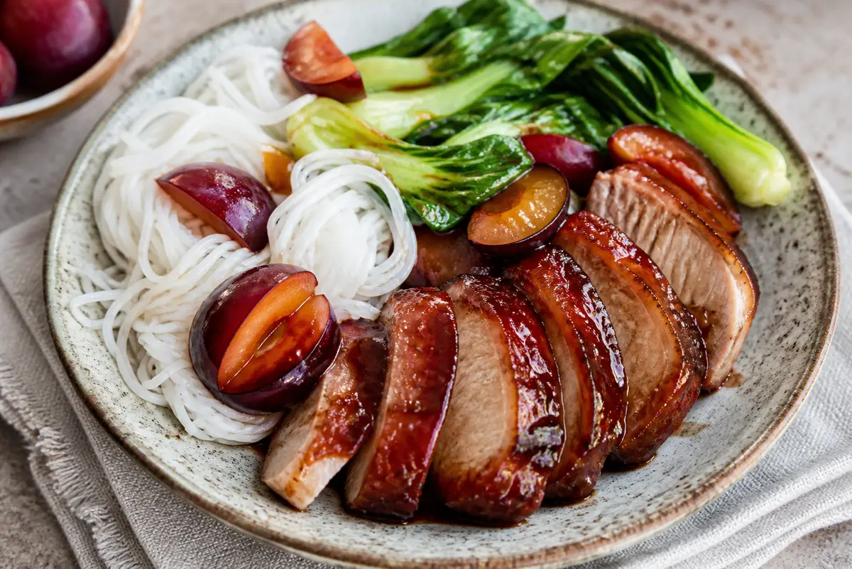 Cerdo glaseado con cinco especias y ciruela sobre fideos de arroz con pak choi salteado