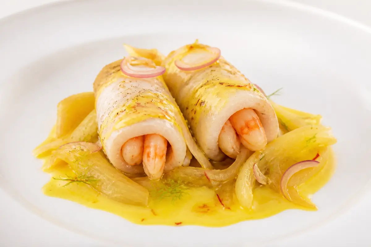 Sole and shrimp rolls in delicate saffron sauce with sautéed fennel