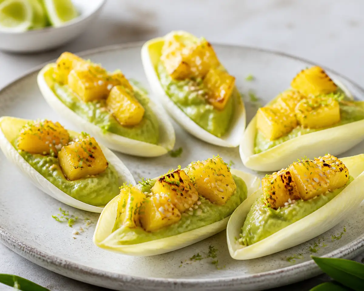 Cucharitas crujientes de endibia con crema de aguacate, piña dorada y sésamo-lima