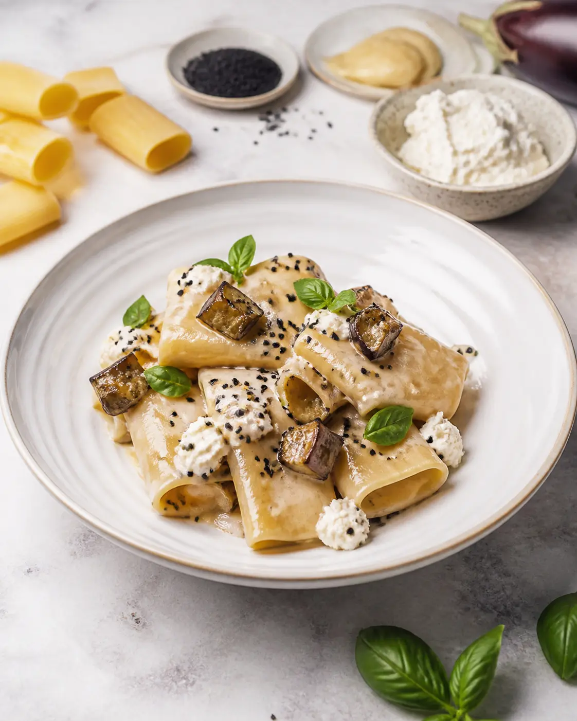 Creamy paccheri with golden eggplant, mild miso and ricotta, finished with black sesame and basil