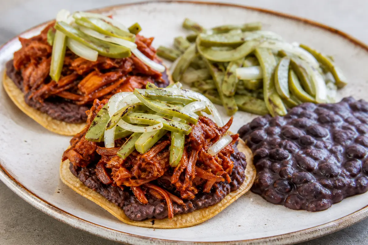 Crispy tostadas with ancho chile mushroom tinga, creamy black beans, and grilled cactus salad
